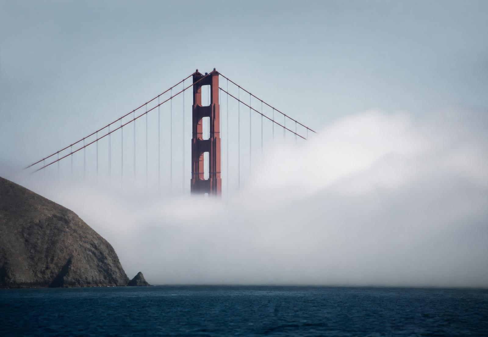 The Golden Gate Bridge tower rising through soft fog